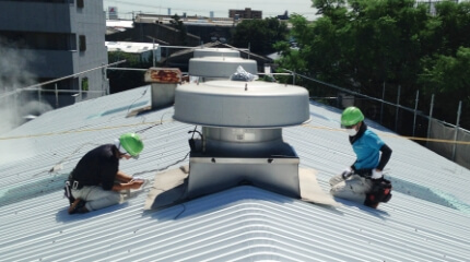 工場・倉庫の劣化したスレート屋根の雨漏りを補修し断熱効果もある防水工事リリーフ工法（カバー工法）なら施工可能な明かり取りやルーフファンがある屋根を施工する様子