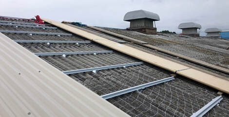 工場・倉庫の劣化したスレート屋根の雨漏りを補修し断熱効果もある防水工事リリーフ工法（カバー工法）を施工中の様子